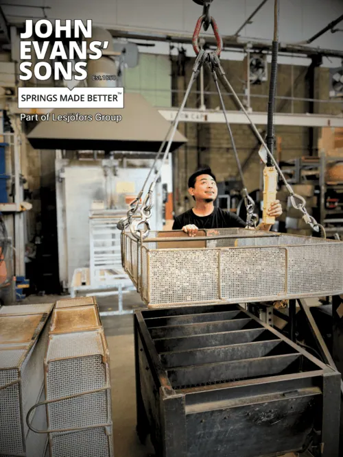 a heater treater lifting a basket of constant force springs for heat treatment.