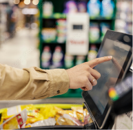 Man touching the screen of point of purchase machine in self-checkout with blurred grocery store background. John Evans’ Sons, Inc. works with display companies, retailers, and merchandisers to optimize and secure their point-of-purchase displays.